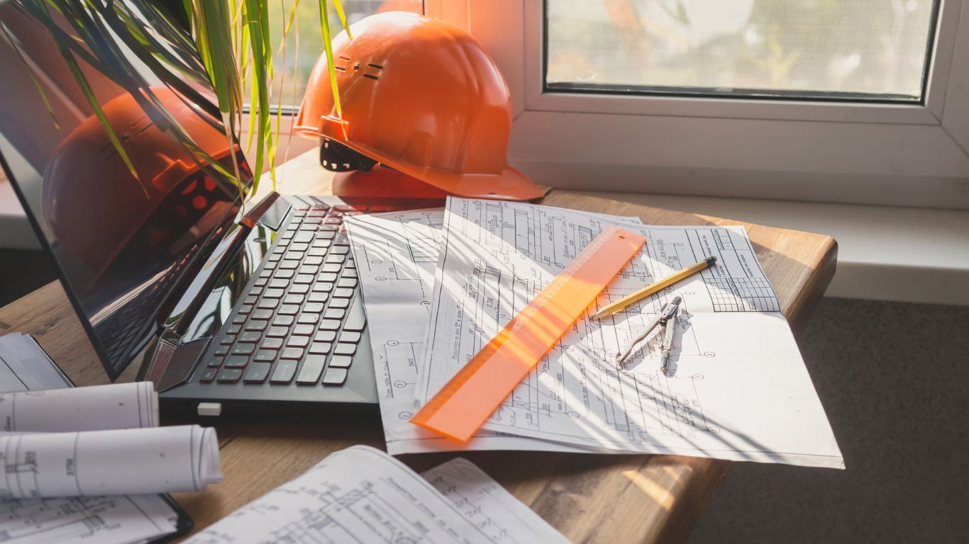 Hard hat, laptop, and blueprints representing project management for an organized contracting team.