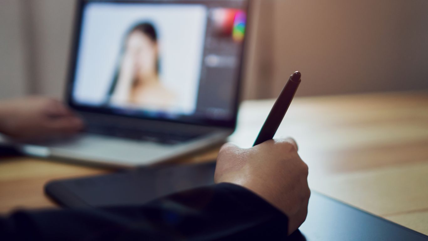 Person editing contractor testimonial content for trade show marketing using a graphics tablet and laptop.