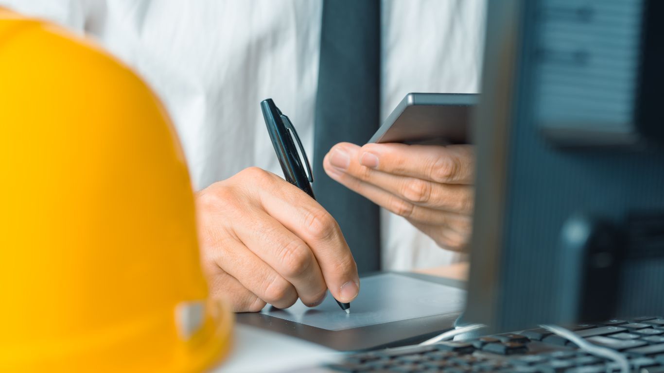 Engineer using a tablet at a desk to manage a contractor sales strategy and keep project details organized.