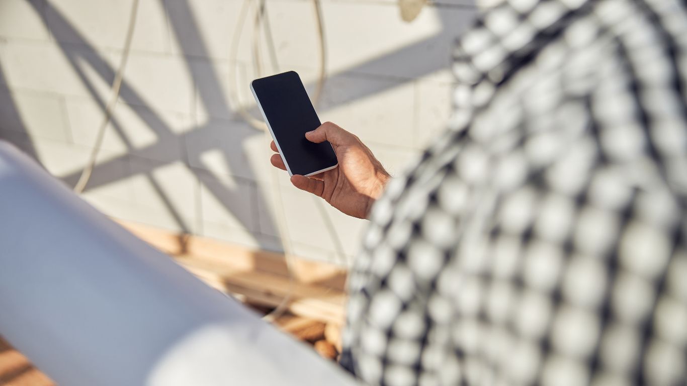 Contractor using a smartphone on site, showing home service sales techniques that improve customer communication.