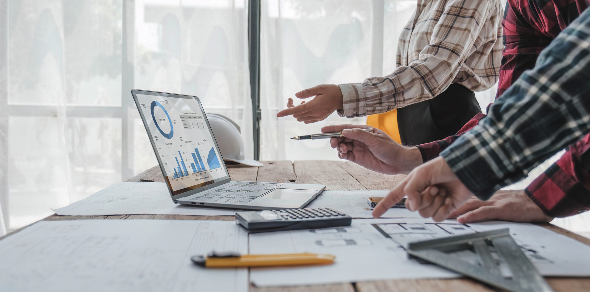 Contractors Analyzing KPI Data and Blueprints on a Desk