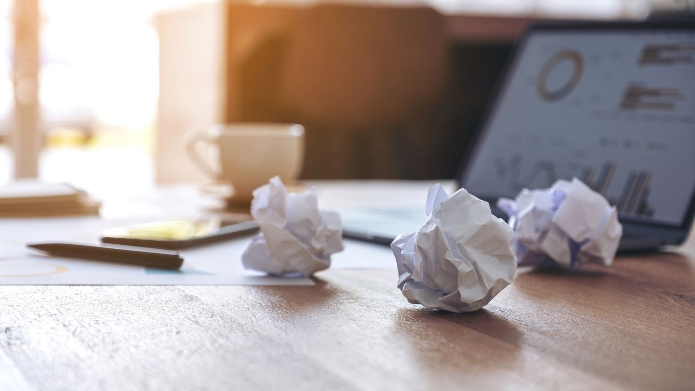 Crumpled paper on an office desk representing manual rework and the hidden costs of disconnected contractor software.