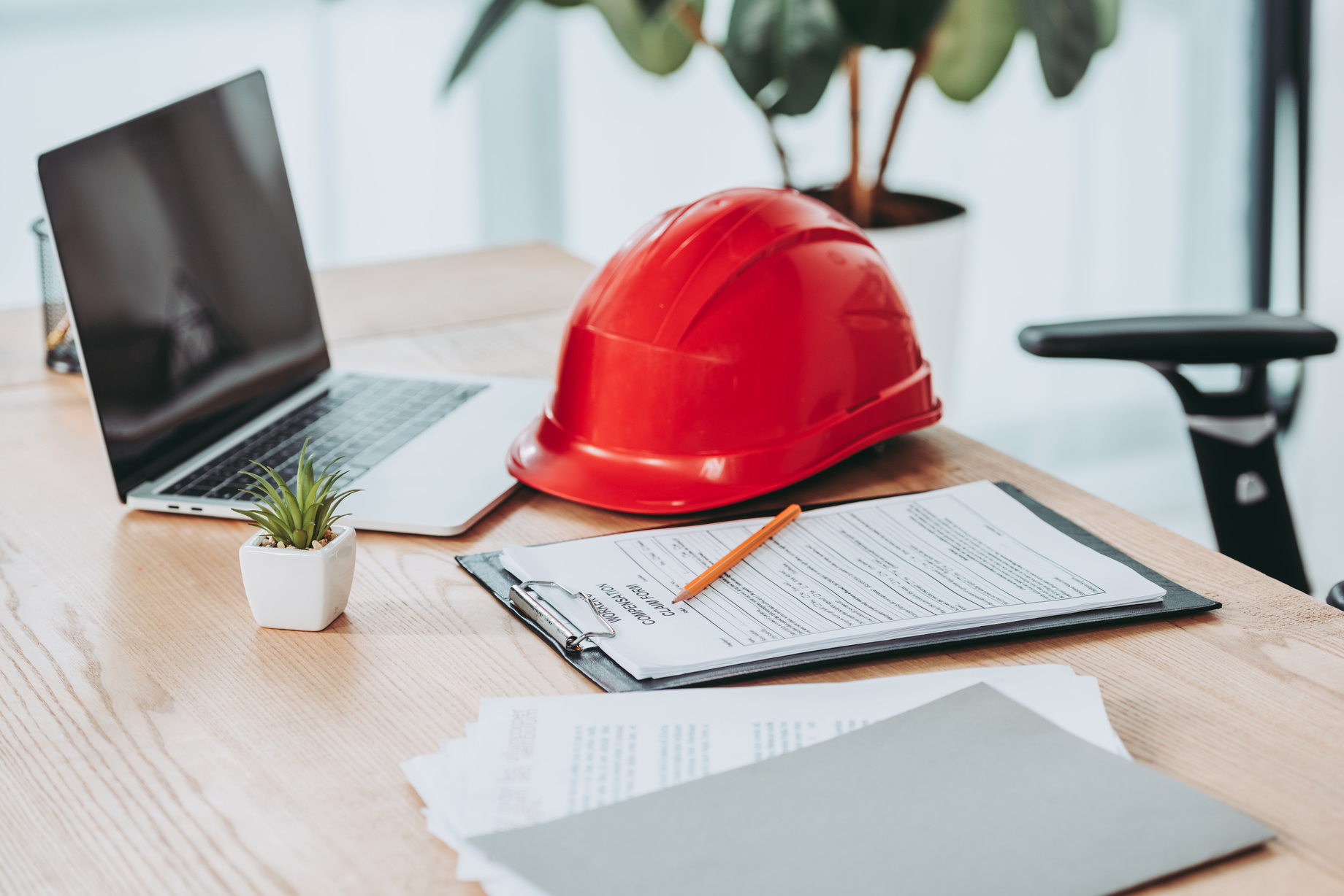Contractor business software evaluation with laptop, hard hat and forms