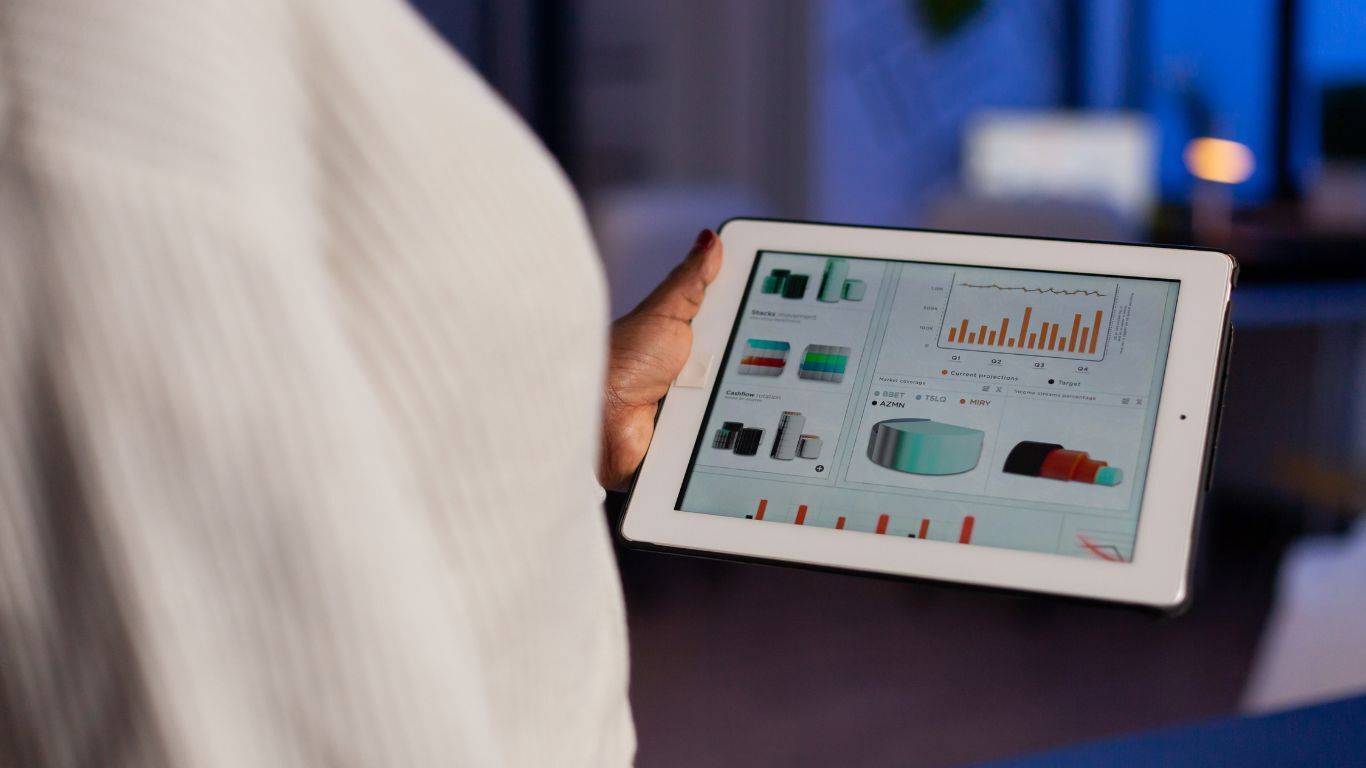 Business professional reviewing reporting charts on a tablet while evaluating payment software features.