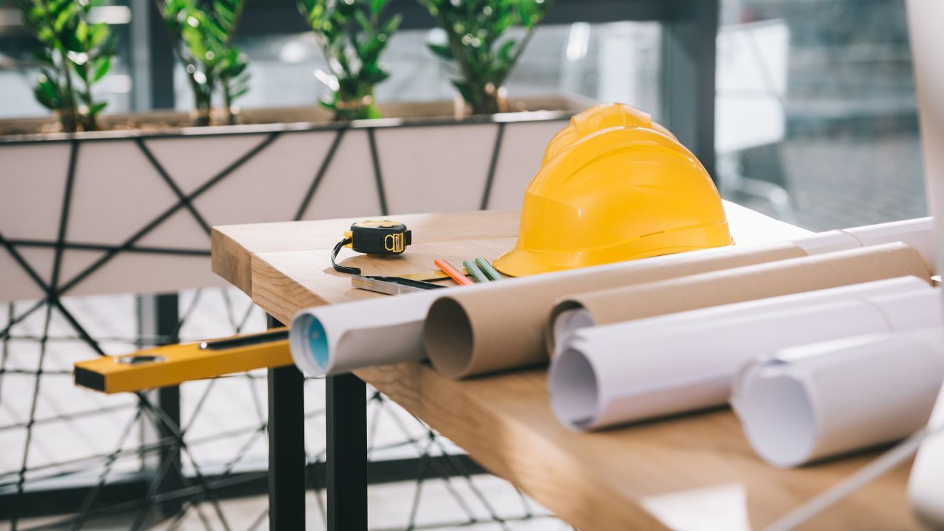 Hard hats and blueprints on a worktable representing seasonal contractor goals and project planning.