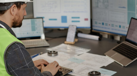 Male Engineer Wearing Hardhat in Office and Using Contractor Dashboard